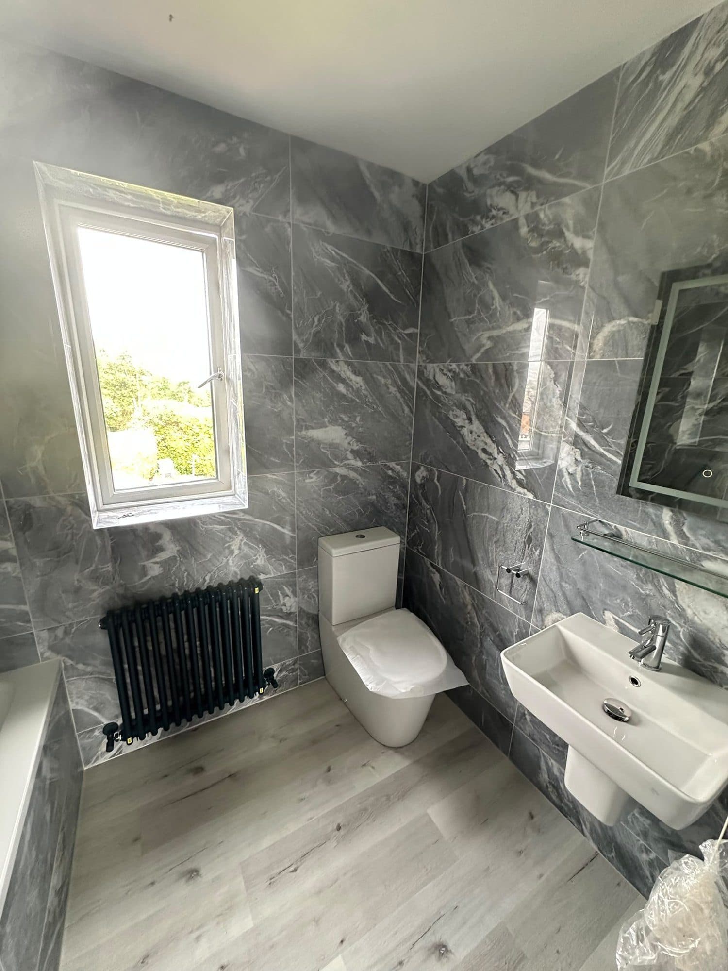 A grey marble-effect bathroom with a black column radiator
